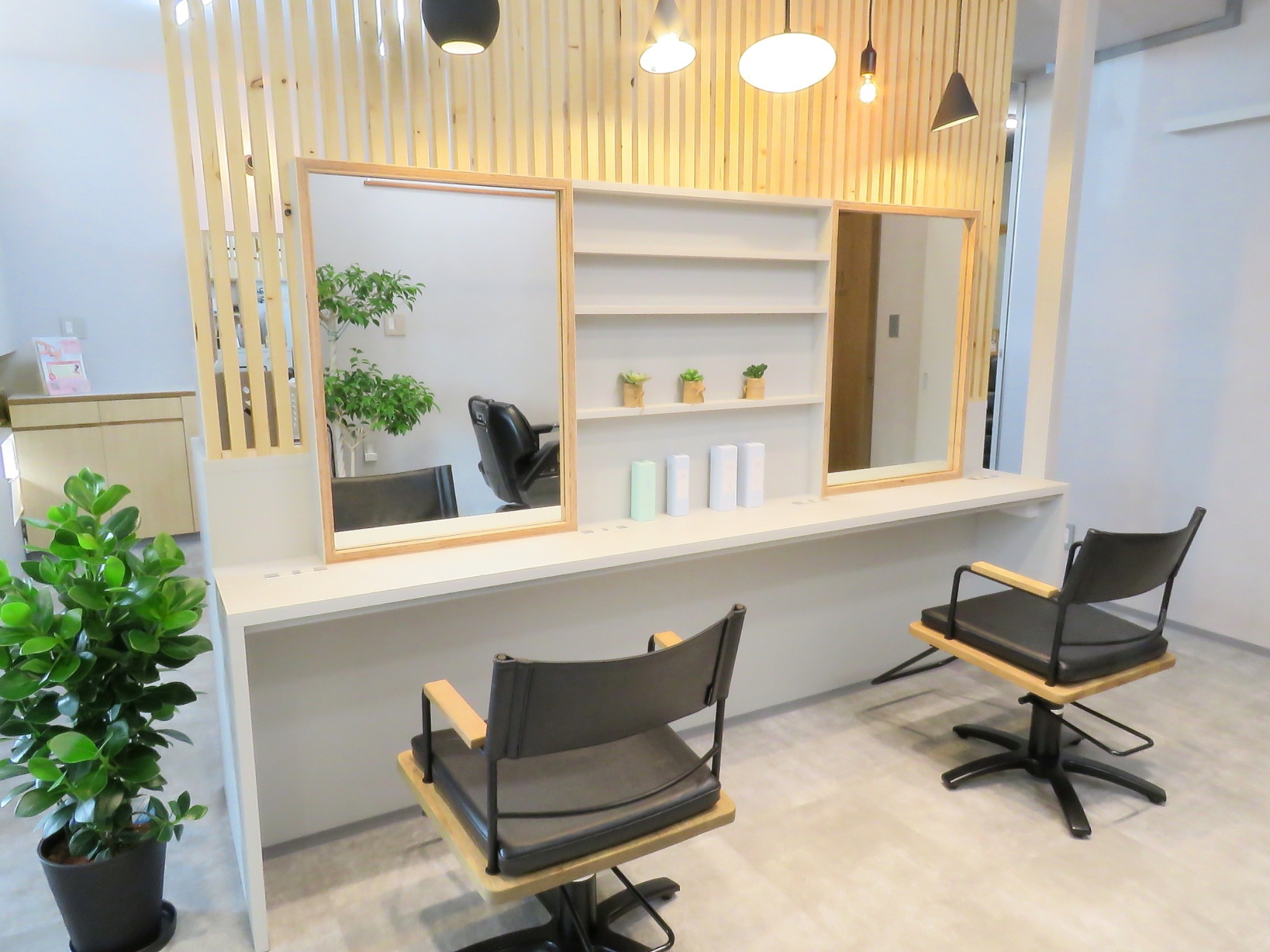 COLOREの美容ブース。大きな鏡と長いテーブルのある落ち着いた店内
